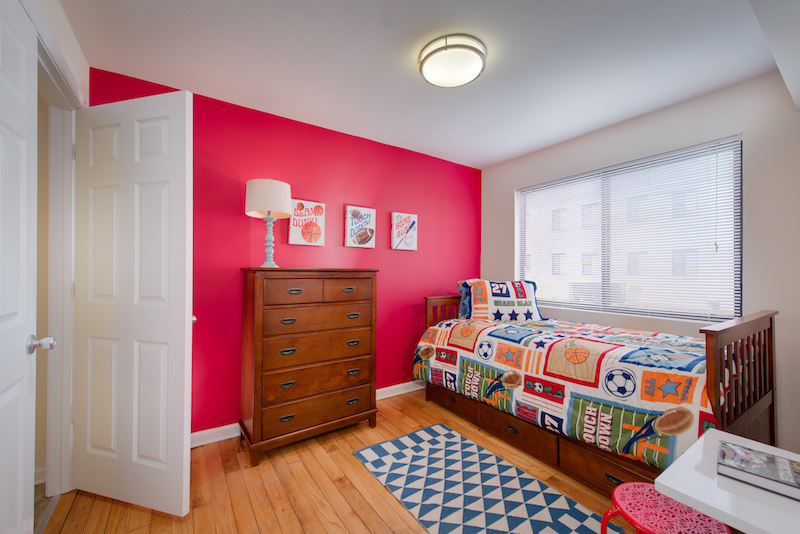 Bedroom with twin bed, a large window, and a red wall